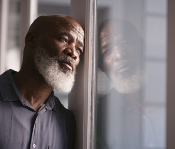 Sad, depression or black man burnout at window with mental health, headache or anxiety in house. Lonely, stress or depressed man thinking for financial problem, health compliance or finance policy